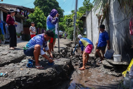 People working with tools and bare hands on torn-up ground wet ground