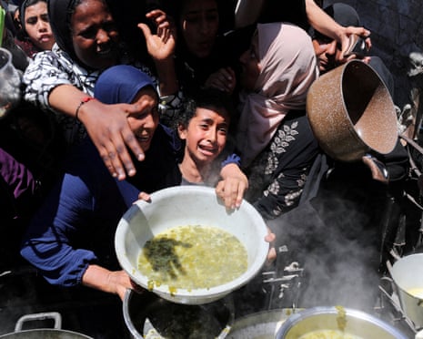 یک فلسطینی در بیت لاهیا، شمال نوار غزه، غذایی را که توسط یک آشپزخانه خیریه پخته شده است، دریافت میکند.