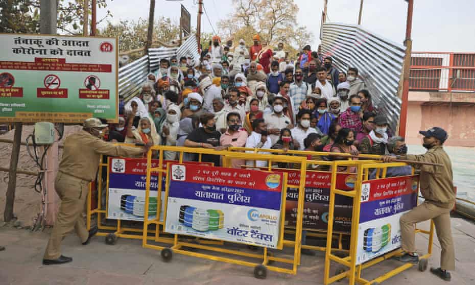 Devotees stand behind barricades as they wait for Naga Sadhu or Naked Hindu holy men to arrive for Shahi snan or a Royal bath during Kumbh mela, in Haridwar, 12 April