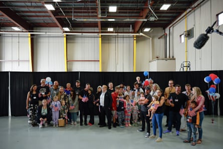 A group of people standing in an airport hangar with red, white and blue balloons.