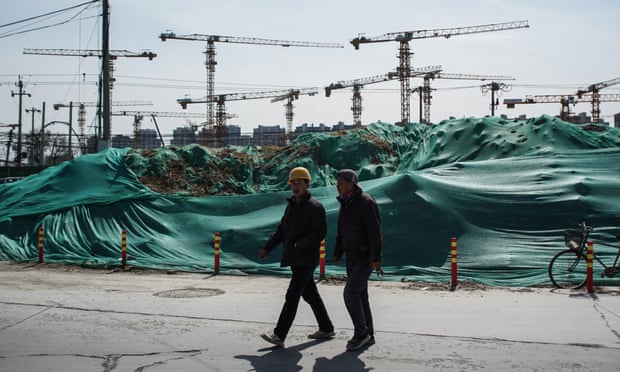 men walk in front of a housing development under construction