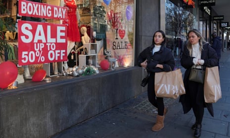 People walk along a shopping street, during the traditional Boxing Day sales in London, Britain.