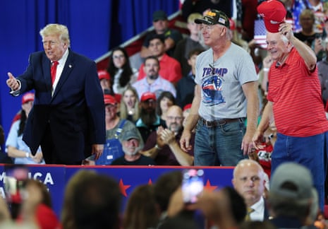 Donald Trump walks past cheering supporters, one holding up a red cap, at a campaign rally