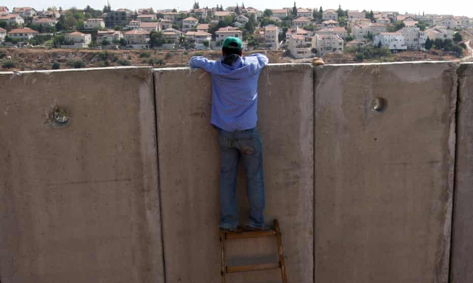A Palestinian youth looks over the West Bank barrier.