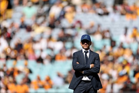 Wallabies coach Les Kiss stands with arms crossed on the field before a crowded stadium