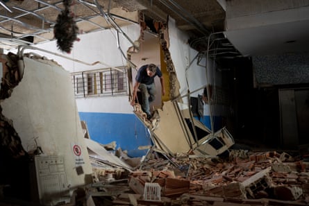 A man walk over rubble inside the remains of a building