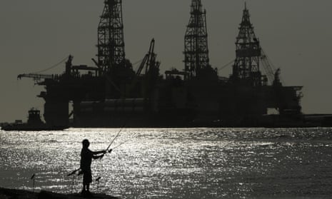 A man fishes near docked oil drilling platforms in Port Aransas, Texas. 