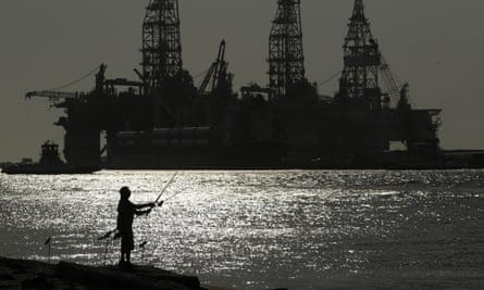 A man wears a face mark as he fishes near docked oil drilling platforms in Port Aransas, Texas.