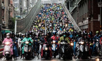 A large number of people on scooters and motorbikes on a bridge