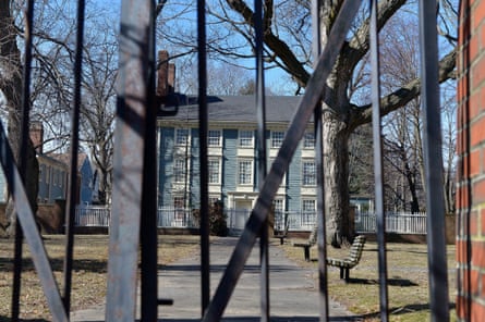A colonial house behind a metal fence.