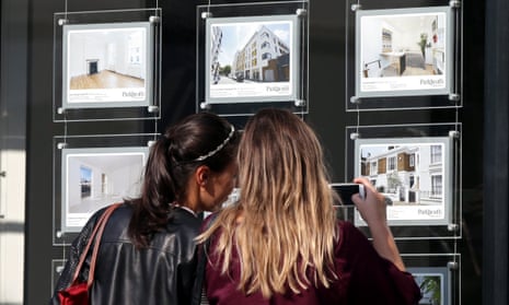 Two young women look at property ads in an estate agent's window