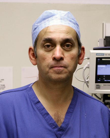 Ara Darzi looks to camera wearing blue scrubs and head covering, serious expression.