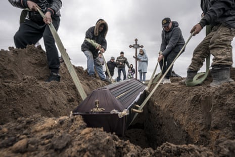 Yryna Chebotok, 26, holds a cross as her grandfather, Volodymyr Rubaylo, 71, is buried at the cemetery in Bucha, Ukraine.