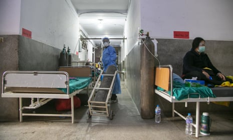 A Nepalese paramedic wheels in an oxygen cylinder as a Covid patient rests on a bed in the corridor of a government-run hospital in Kathmandu