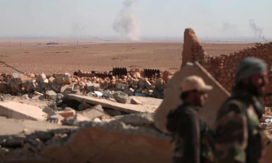Syrian Democratic Forces fighters stand near a destroyed building north of Raqqa