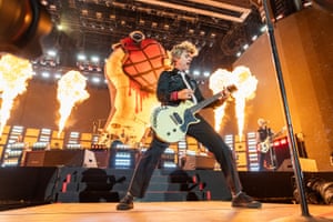 The frontman plays his guitar as fire shoots into the air behind him