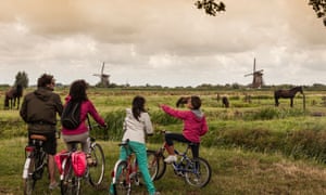 A family by bicycle takes a view of Kinderdijk.