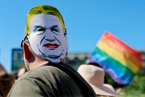 A mask depicting Hungarian prime minister Viktor Orban with dyed yellow hair and red lips on the back of a person’s head