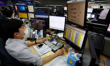 A trader wearing a protective mask works in front of monitors at the KEB Hana Bank in Seoul, South Korea, today