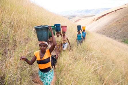 A group of women carrying water climb up a hill on their way home to the village of Miarinarivo, Madagascar