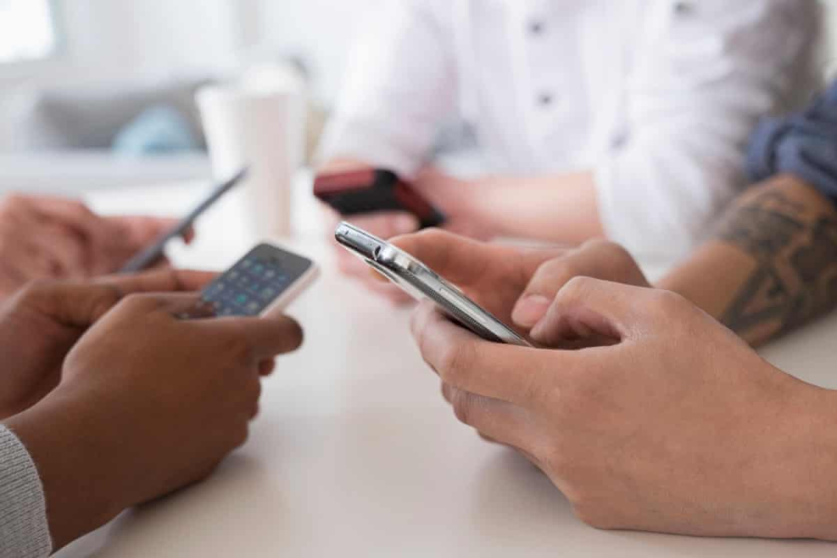 Close up of friends texting with cell phones at tableGettyImages-557475765