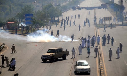 Pakistani security forces fire teargas shells toward PTI supporters during a clash close to the Islamabad police headquarters where Khan was being held