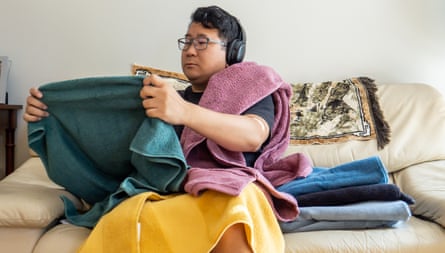 A person folding towels while sitting inside
