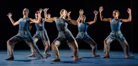 A group of dancers on stage with their arms raised