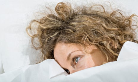 Tired woman with unruly hair lies in bed