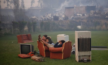 A young couple rest in a football field after a forest fire devastated Santa Olga.