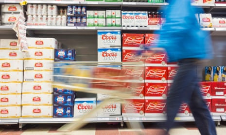 A blurred image of a person with a shopping trolley in supermarket drinks aisle.