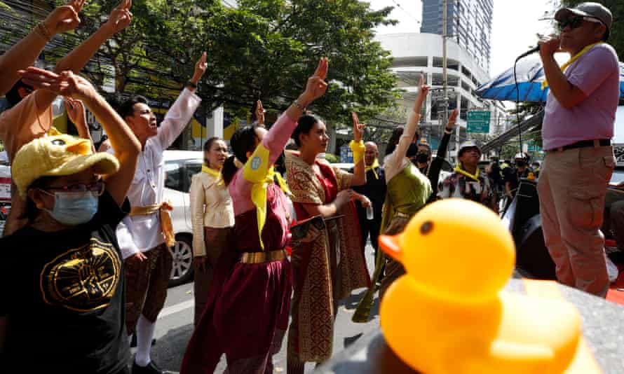 Anti-government protesters flash a three-finger salute – a gesture used adopted by protesters from the Hunger Games films – as they gather in support of people detained under the lese-majesty law at a police station in Bangkok.