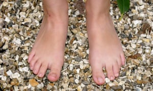 The bare feet of a person standing on pebbles. Barefoot walk for Family section