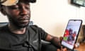 Pato, a migrant from Cameroon, holds a phone showing a picture of him with his family as he gives an interview at an undisclosed location near Tripoli.