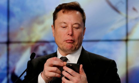 Elon Musk looks at his mobile phone during a post-launch SpaceX news conference