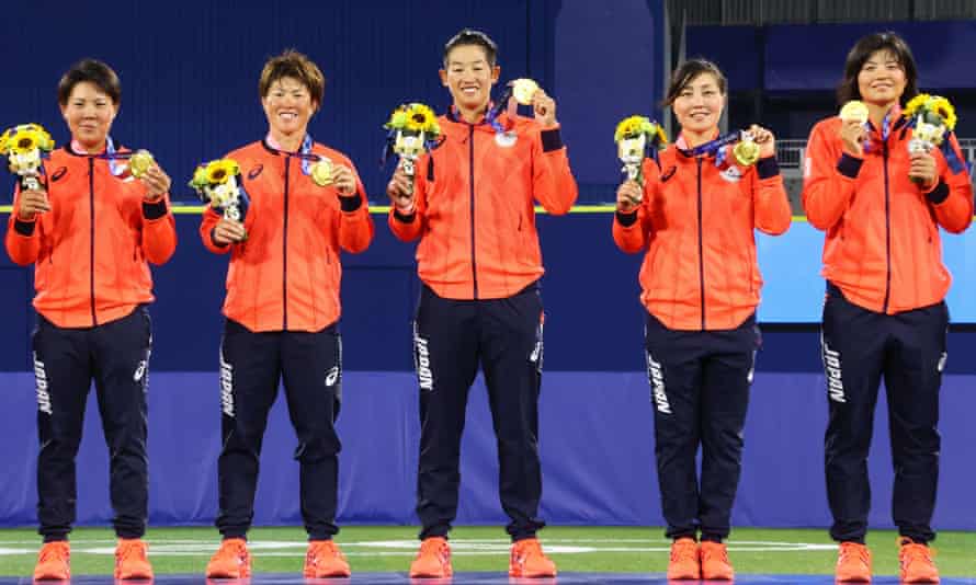 Japan’s softball players stand with their gold medals on the podium.