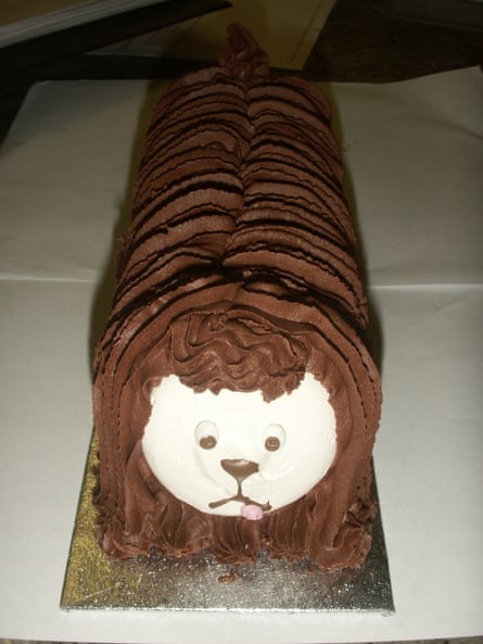 A long medium brown chocolate log cake with a white face of a dog at the forefront