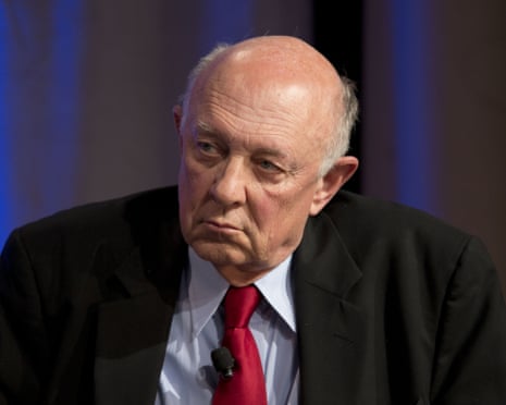 man in suit with microphone clipped to tie looks to side while seated on stage