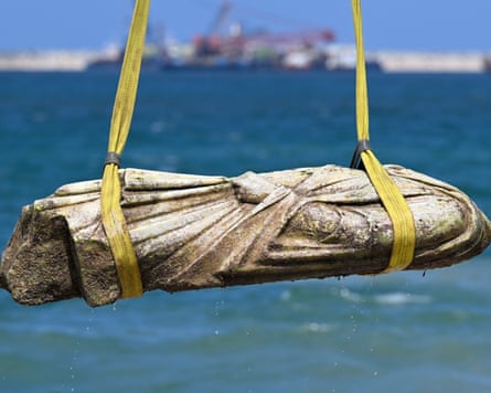 A close shot of a statue being lifted from the water by a crane