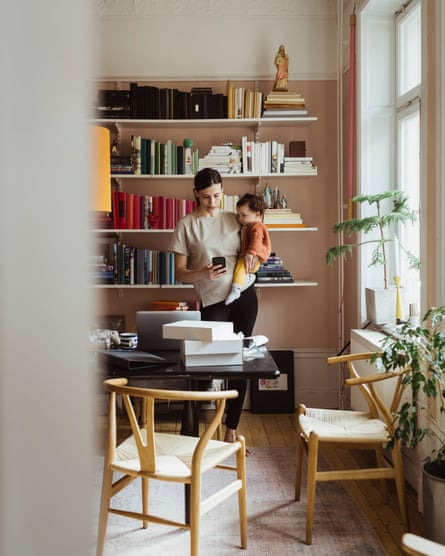 Female entrepreneur using smart phone with toddler son at home office