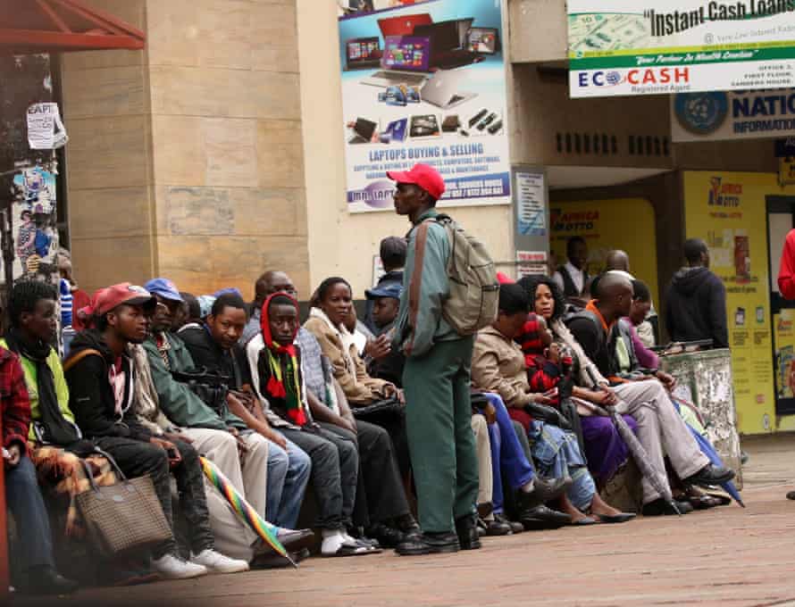 People queue to withdraw money outside a bank in Harare