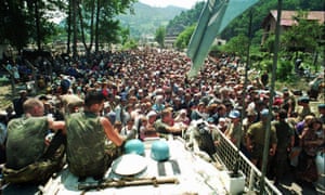 cascos azules holandeses de la ONU se sientan encima de un transporte blindado de personal como refugiados musulmanes de Srebrenica se reúnen en el cercano pueblo de Potocari en julio de 1995.