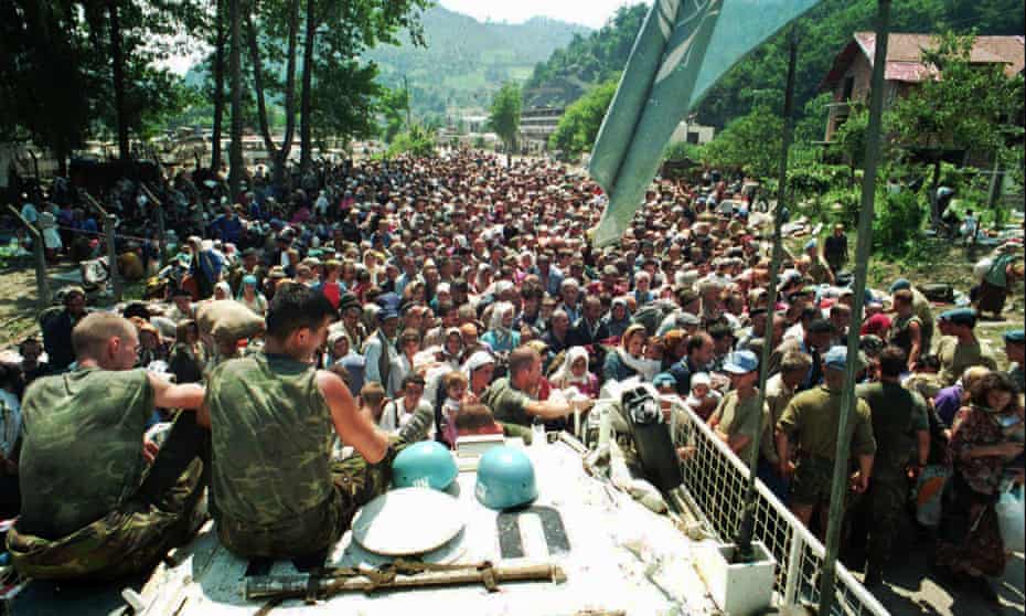 Dutch UN peacekeepers sit on top of an armoured personnel carrier as Muslim refugees from Srebrenica gather in the nearby village of Potocari in July 1995.