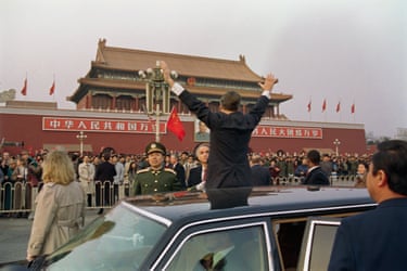 President George Bush stands up in car and waves out of skylight in Tiananmen Square