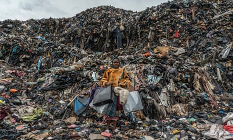 An African girl wearing fake fur in front of huge piles of waste in a landfill