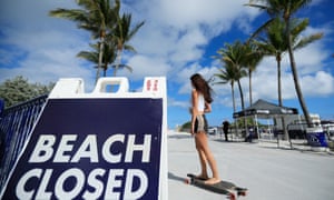 A skateboarder passes a ‘Beach Closed’ sign on the boardwalk in Miami Beach, Florida, on 20 March. Some Republican mayors in the state had kept beaches open during spring break.