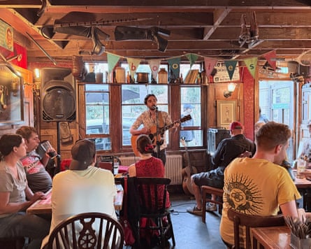 The musician Isaac Neilson playing acoustic guitar at a seated gig