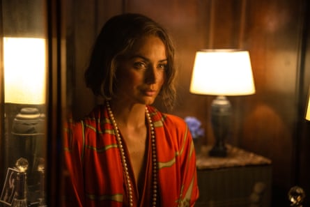 woman in red robe looks ahead in dimly lit room