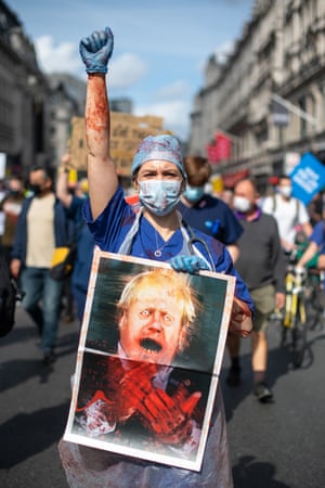 An NHS worker holds a grotesque caricature of the prime minister, Boris Johnson, during a protest in London against low pay in the health service.