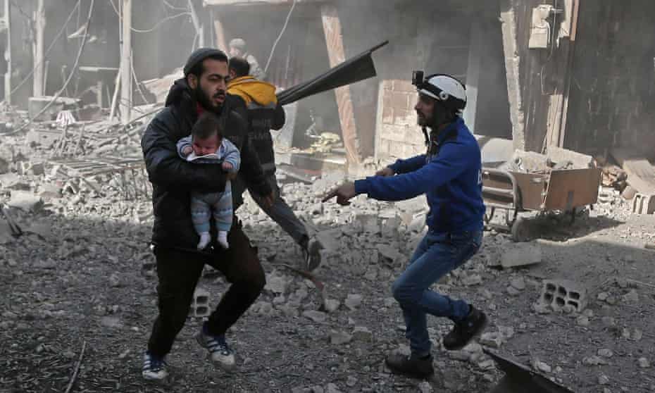A Syrian man carries an baby injured by the government attack in eastern Ghouta